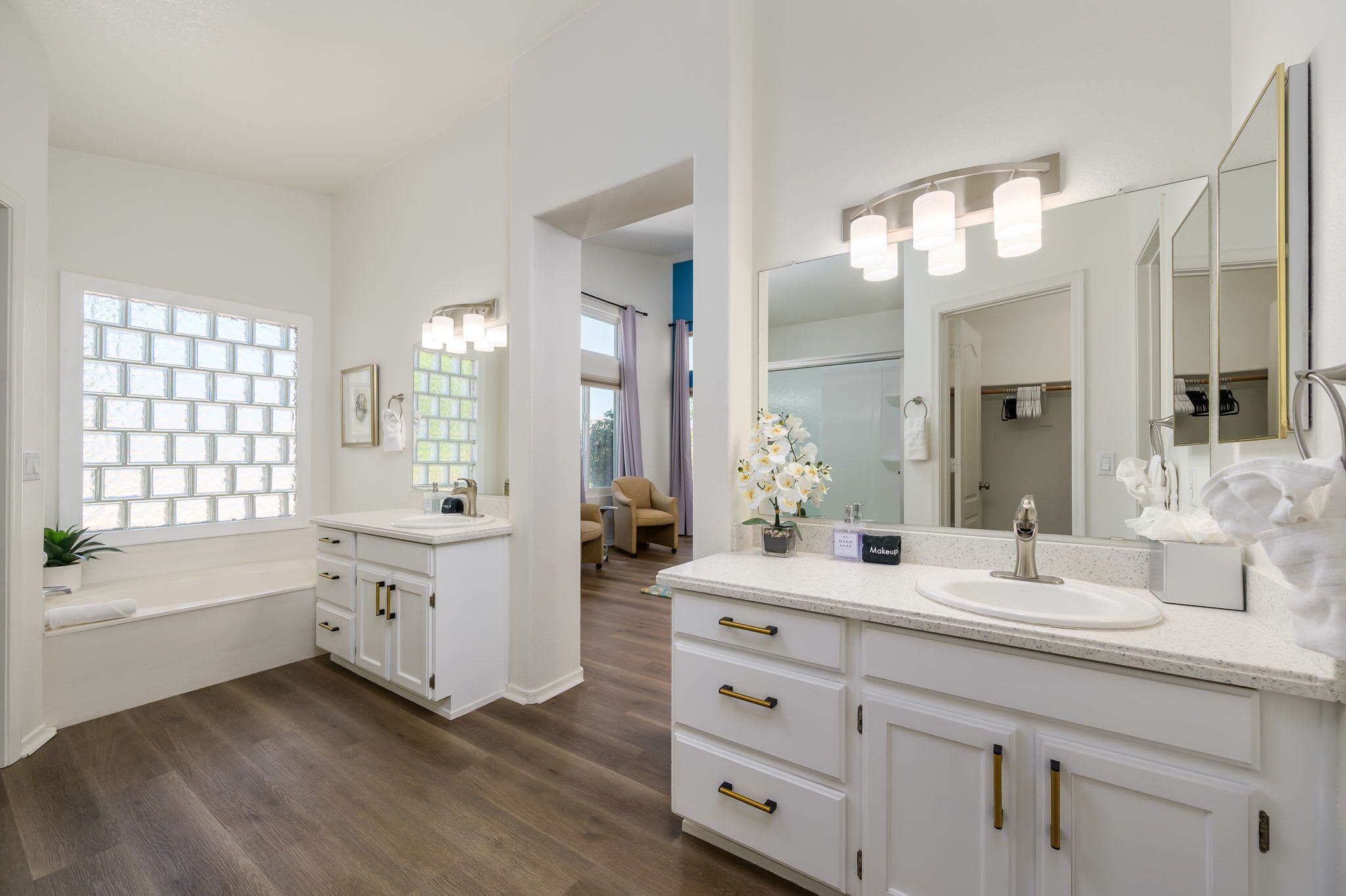 A modern bathroom with a large mirror, two sinks, and a vanity with drawers.