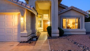 Una casa residencial con garaje, puerta principal y ventana con luz interior.
