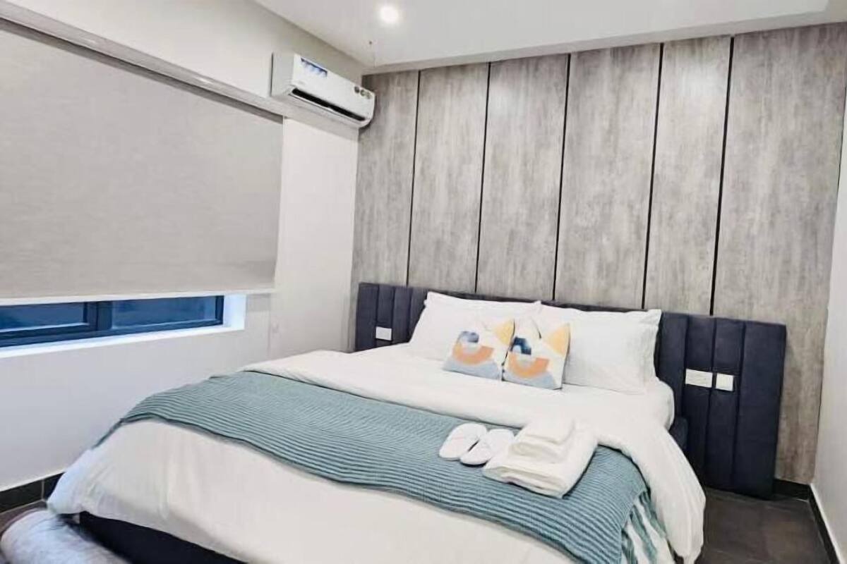A modern hotel room with a bed, a window, and a wall-mounted air conditioner.
