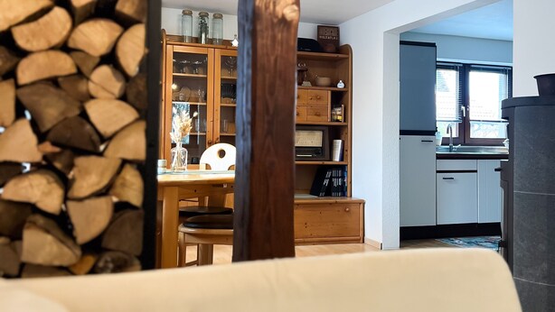 A living room with a wooden coffee table, a sofa, and a kitchen in the background. - Immergrün Apartment – Your Relaxing Retreat with Heart & Dog in the Countryside (Stetten am kalten Markt)