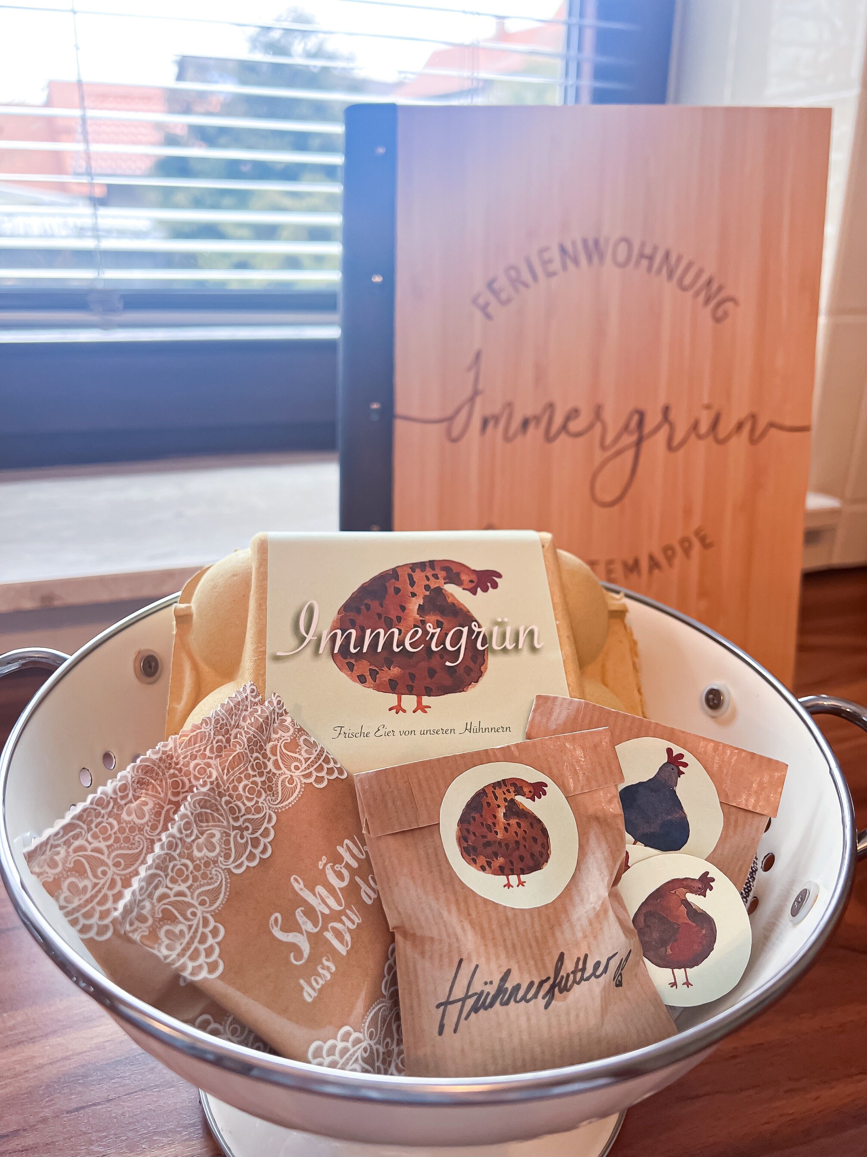 A metal bowl filled with various packaged items, including a box labeled 'Immergrün' and others with chicken illustrations.
