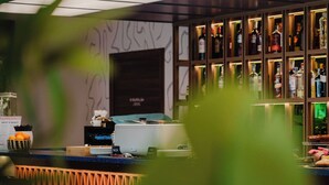 A bar named 'MOKO' with a modern design, a counter with a coffee machine, and a variety of bottles on shelves.