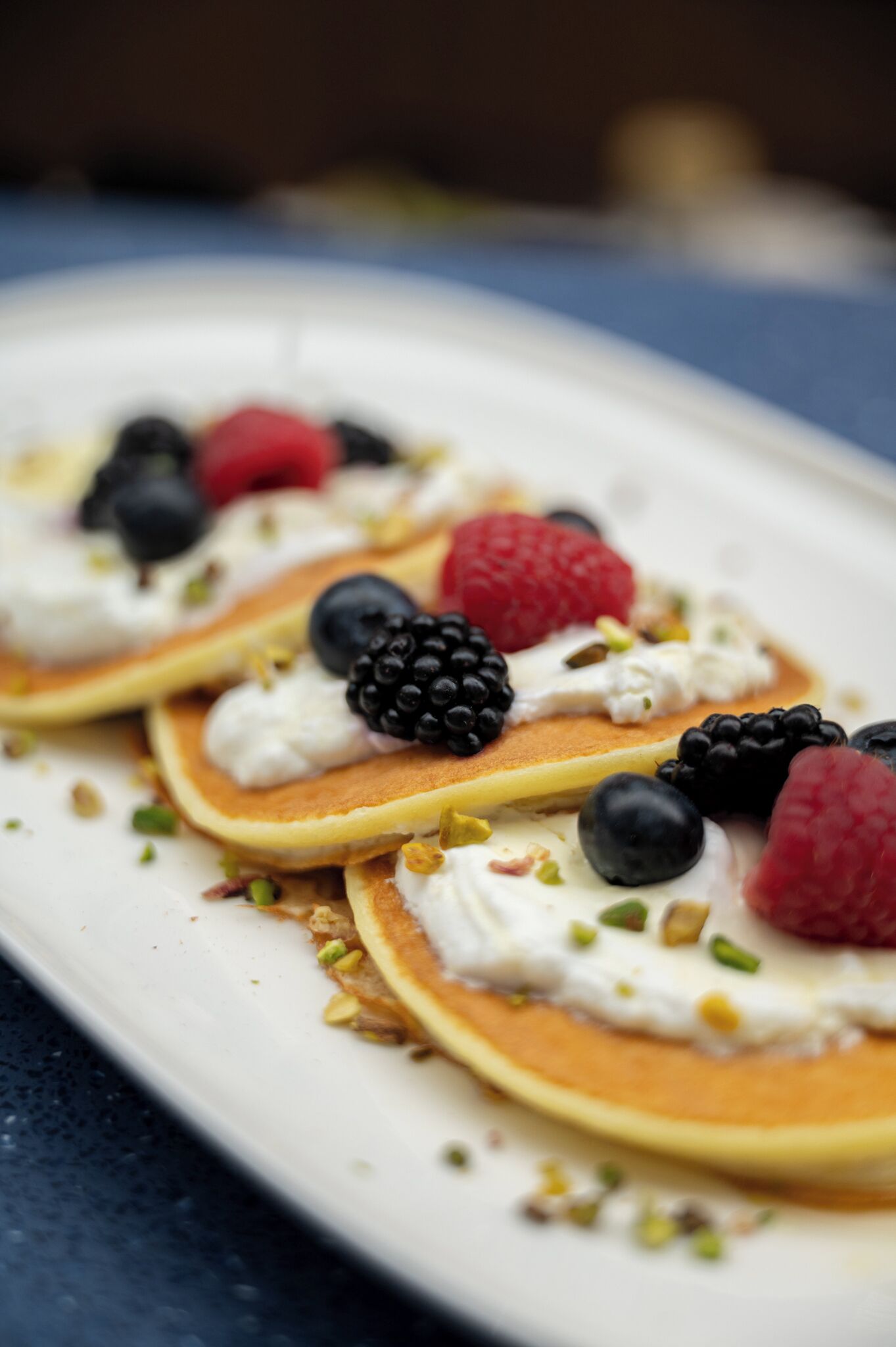 A dessert plate with pancakes topped with whipped cream and berries.