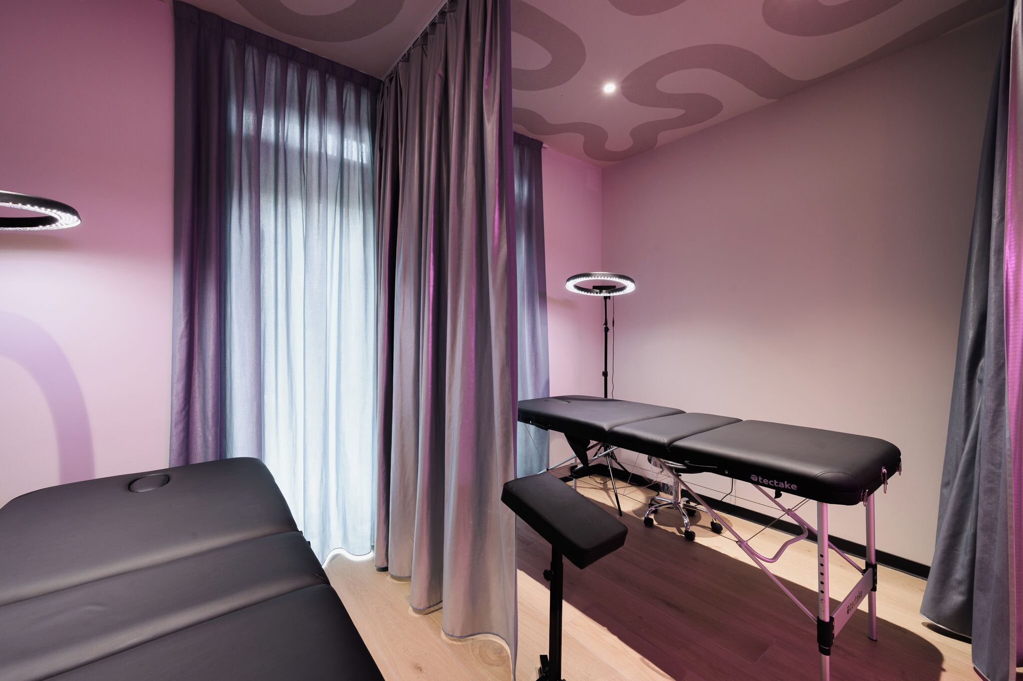 A room with a bed, a small table, a lamp, and a curtain.