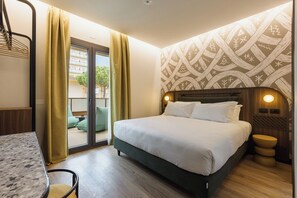 A hotel room with a bed, a desk, a chair, a window with curtains, and a patterned wall. - MOKO LIFESTYLE HOTEL-Nuova apertura 2026 (Milano Marittima)