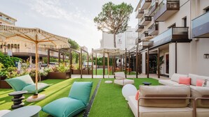A courtyard with artificial grass, outdoor seating, and a pergola.
