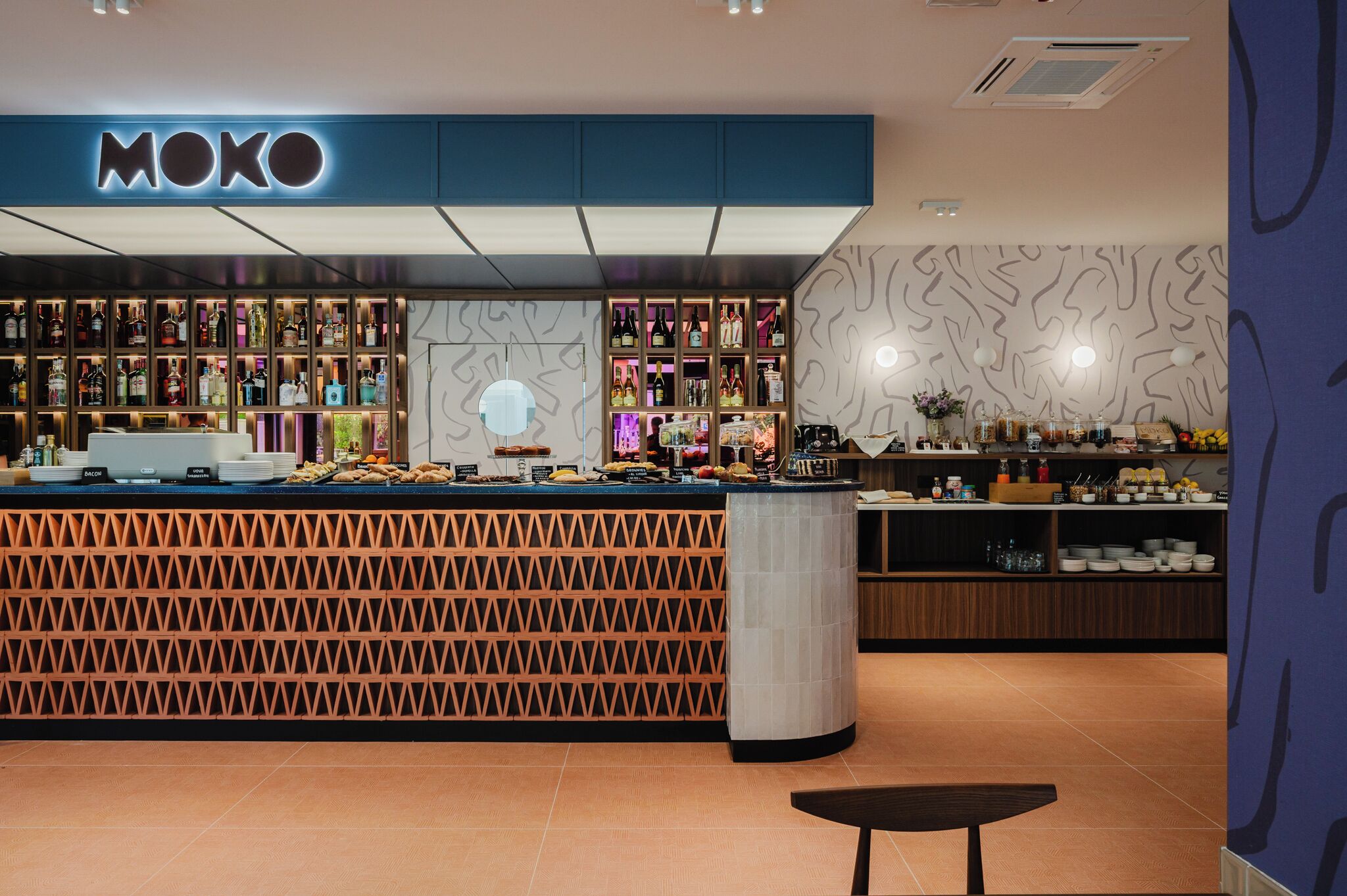 Un bar MOKO con un diseño moderno, una variedad de botellas de licor y una barra con aperitivos.