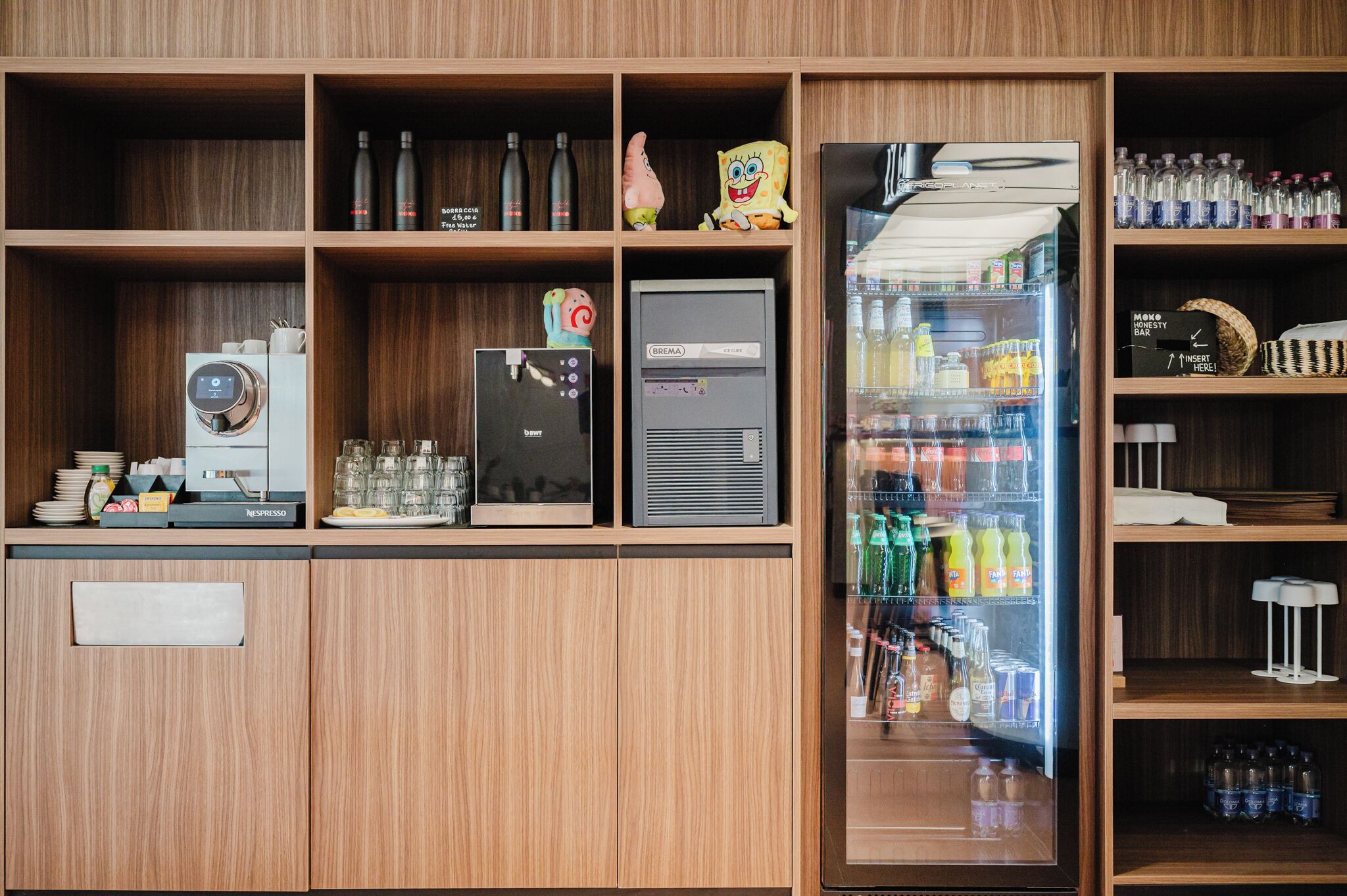 Une petite cuisine équipée d’une machine à café, d’un réfrigérateur et d’un distributeur de boissons.