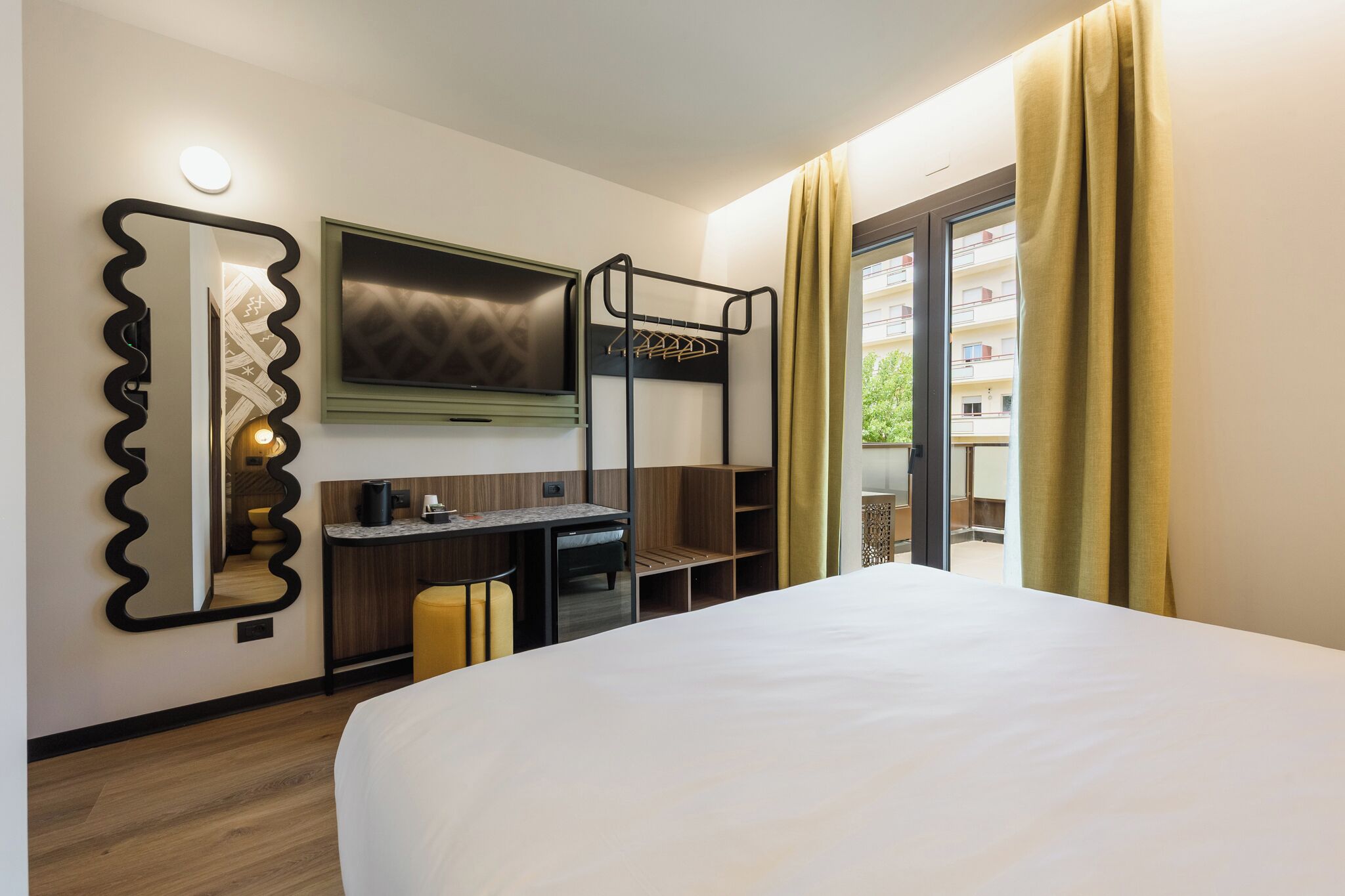 A hotel room with a bunk bed, a desk, a chair, a mirror, and a TV.