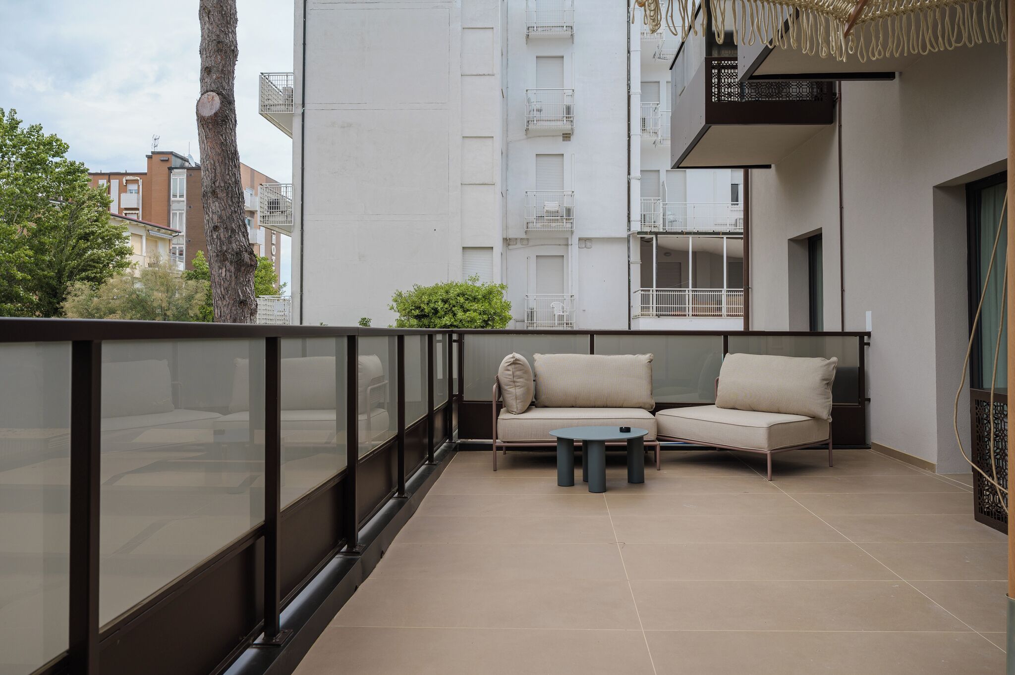 A balcony with a sofa, two small tables, and a glass railing.