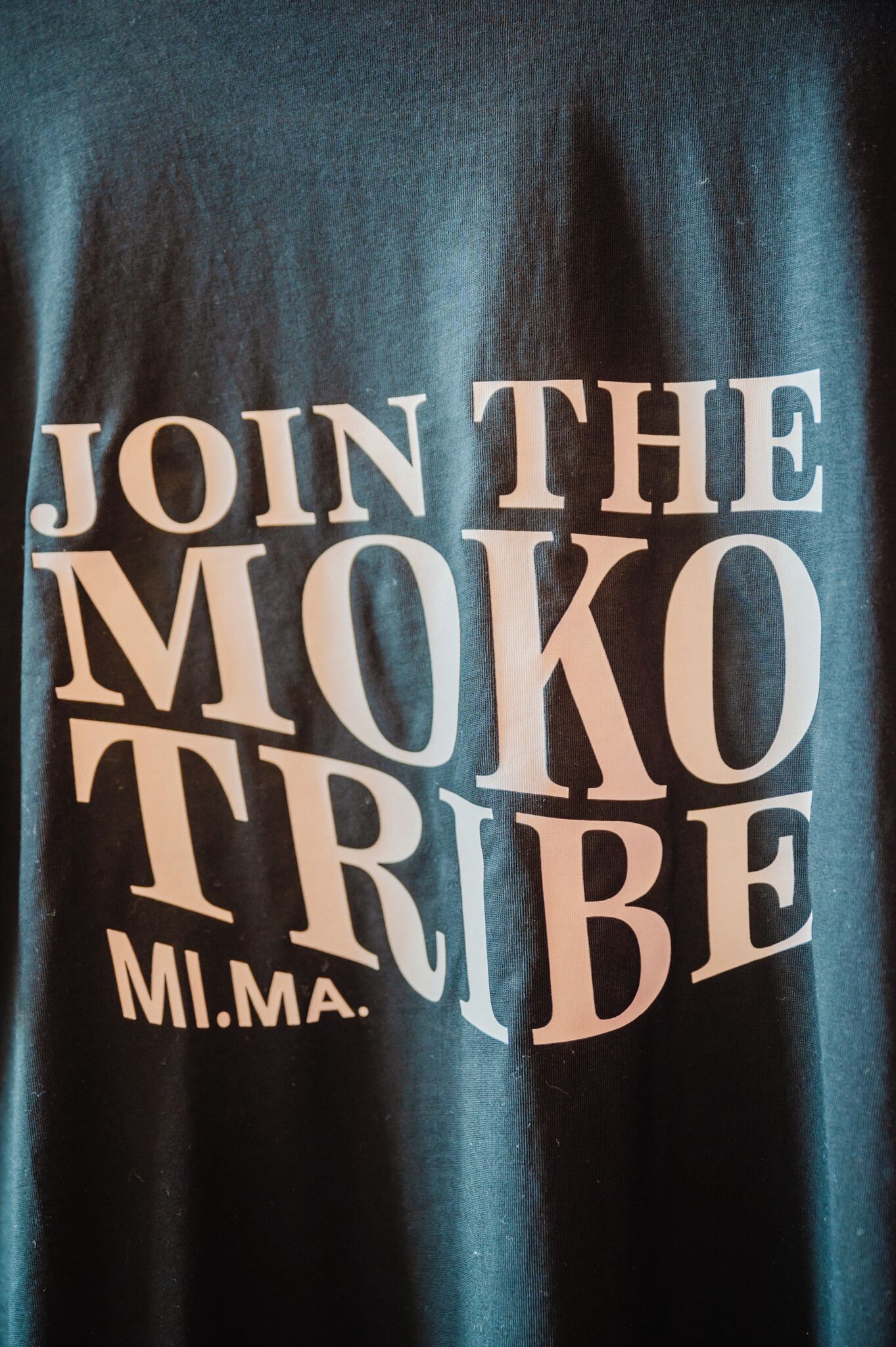 A dark blue fabric with the text 'JOIN THE MOKO TRIBE MI.MA.'