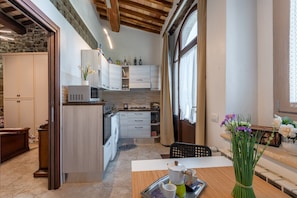 A compact kitchen with modern appliances, a dining area with a table and chairs, and a view of the outdoors through a window. - Sant'Antimo Montalcino Holiday Home with Garden View and Private Parking (Montalcino)