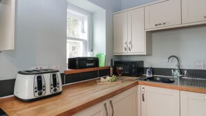 A kitchen with a toaster, a bread box, a microwave, a sink, and cabinets. - Ardpatrick South Lodge (Tarbert)
