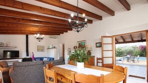 A living room with a wooden dining table, chairs, a sofa, and a TV. - Holiday Home 'Oliveres' with Mountain View, Wi-Fi and Air Conditioning (Illes Balears)