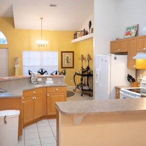 A compact kitchen with a built-in oven, a refrigerator, and a sink. - Tipsy Turtle | 4BR/2 BA l Heated Pool | Sleeps 8 (Cape Coral)