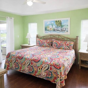 A bedroom with a bed, a painting on the wall, and a window with blinds. - Tipsy Turtle | 4BR/2 BA l Heated Pool | Sleeps 8 (Cape Coral)