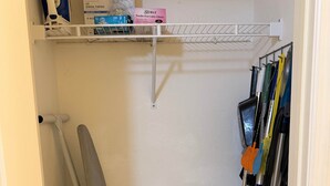 Un cuarto de lavado con un estante que contiene productos de limpieza, un trapeador y una escoba.