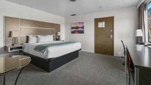 Ein Hotelzimmer mit Bett, Nachttisch, Lampe und einem Gemälde an der Wand.