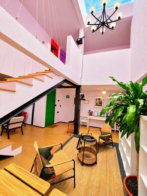 Ein geräumiger Innenraum mit hoher Decke, einer Treppe und einer Sitzecke mit Stühlen und einem Tisch.