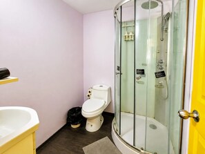 Ein Badezimmer mit einer Duschkabine, einer Toilette und einem Waschbecken.