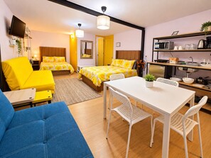 Ein Hotelzimmer mit einem Bett, einem Esstisch, einer Couch und einer Küchenzeile.