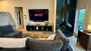Una sala de estar moderna con televisor de pantalla plana, sofás grises, una mesa de centro y una chimenea.