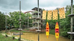 Ein Abenteuerpark im Freien mit Seilbrücken, einer Holzkonstruktion und einem ruhigen Fluss.