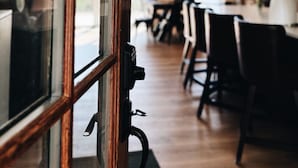 Vista a través de una ventana que muestra un comedor con ventilador de techo, una mesa y sillas.