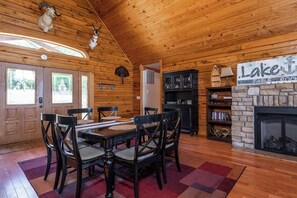 Ein Interieur einer Holzhütte mit Esstisch, Stühlen, Kamin und einem Schild mit der Aufschrift 'Lake Table Rock'.