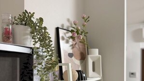 Cocina moderna con microondas, repisas blancas y una planta en maceta.