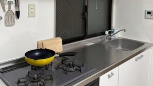 Cocina moderna con estufa a gas, pileta de acero inoxidable y muebles altos blancos.