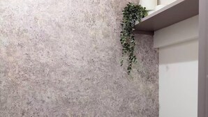 Un baño con pared texturizada, inodoro, lavamanos y una planta colgante.
