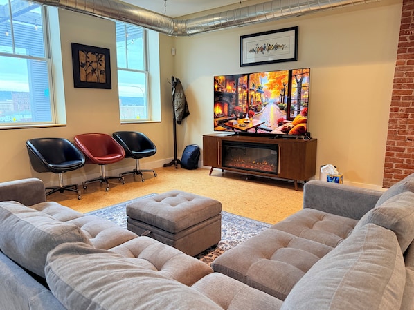 A cozy living room with a fireplace, comfortable seating, and a large TV.