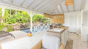 Ein überdachter Außenbereich mit Pool, Holzterrasse und Barbereich.