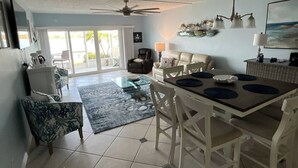 A spacious living area with a dining table, chairs, a ceiling fan, and a view through glass doors to an outdoor patio. - Paradise on the Isles - Stunning Waterfront Views - Pool & Dock Steps Away (Naples)