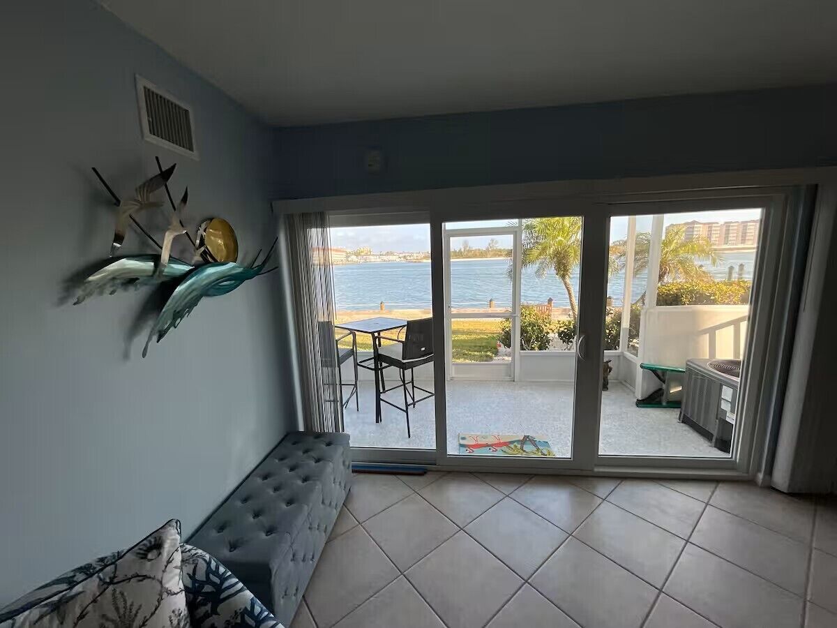 Een kamer met uitzicht op zee, een schuifdeur, een comfortabele bank en een kleine tafel.