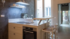 Una cocina con una isla central, taburetes de bar blancos, horno empotrado y una ventana que proporciona luz natural.