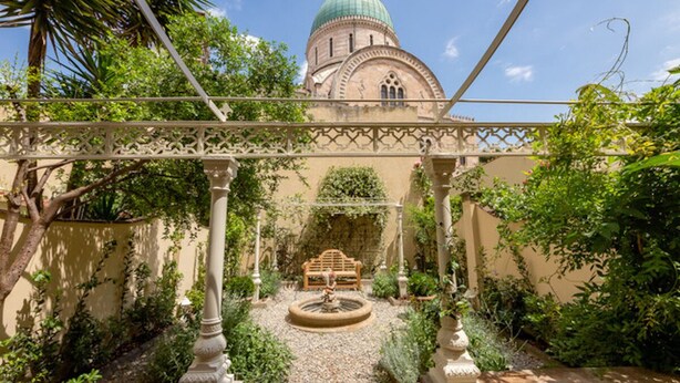 Un patio con una fuente, un banco de madera y un edificio con cúpula.