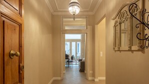 Un pasillo con puerta de madera, un candelabro y un banco.