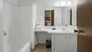 Une salle de bain avec une douche, un lavabo, un miroir et une porte.