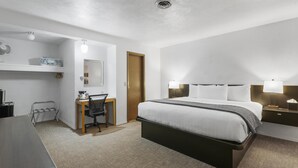 Une chambre d’hôtel avec un lit, un bureau, une chaise et une petite table.