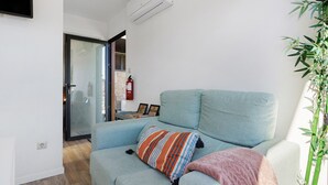 Een woonkamer met een bank, een brandblusser en een wandairconditioner.