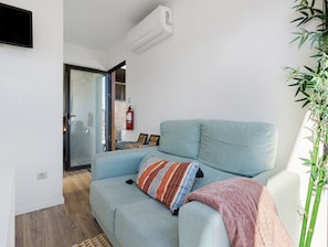 Una sala de estar con un sofá, un extintor y un aire acondicionado instalado en la pared.