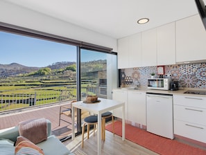 Una cocina moderna con un ventanal grande, armarios blancos y vistas a un viñedo.
