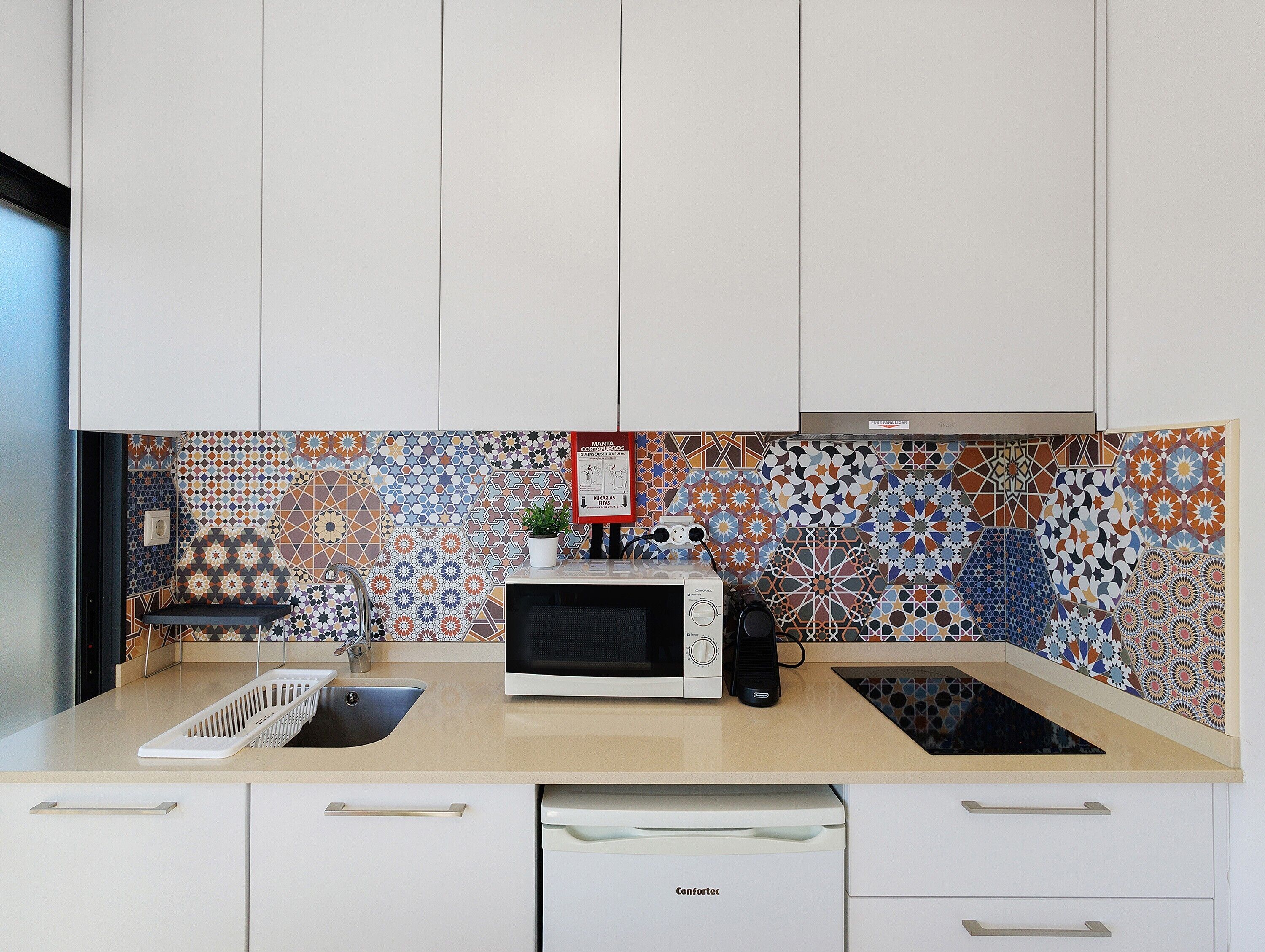 Una cocina con armarios blancos, microondas, fregadero y lavavajillas.