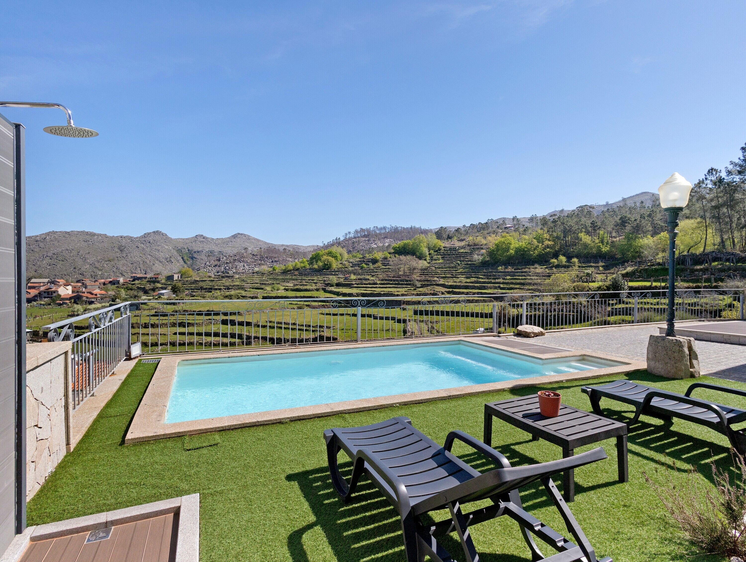 Ein Schwimmbad mit Blick auf eine Treterrasse und Berge.