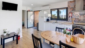 A modern kitchen with a dining area, a TV mounted on the wall, and a window with a view. - Holiday Home 'Casa Dona Florinda - Ermida, Pnpg' with Shared Pool, Shared Garden and Wi-Fi (Ermida)