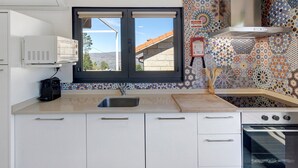 A kitchen with a window, white cabinets, a stainless steel sink, a stove, and a decorative tiled backsplash. - Holiday Home 'Casa Dona Florinda - Ermida, Pnpg' with Shared Pool, Shared Garden and Wi-Fi (Ermida)