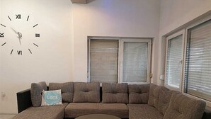 Una sala de estar moderna con un sofá modular, una mesa de centro redonda y un reloj de pared.