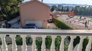 Edificio residencial con garaje, un patio de juegos con toboganes y vistas a montañas al fondo.